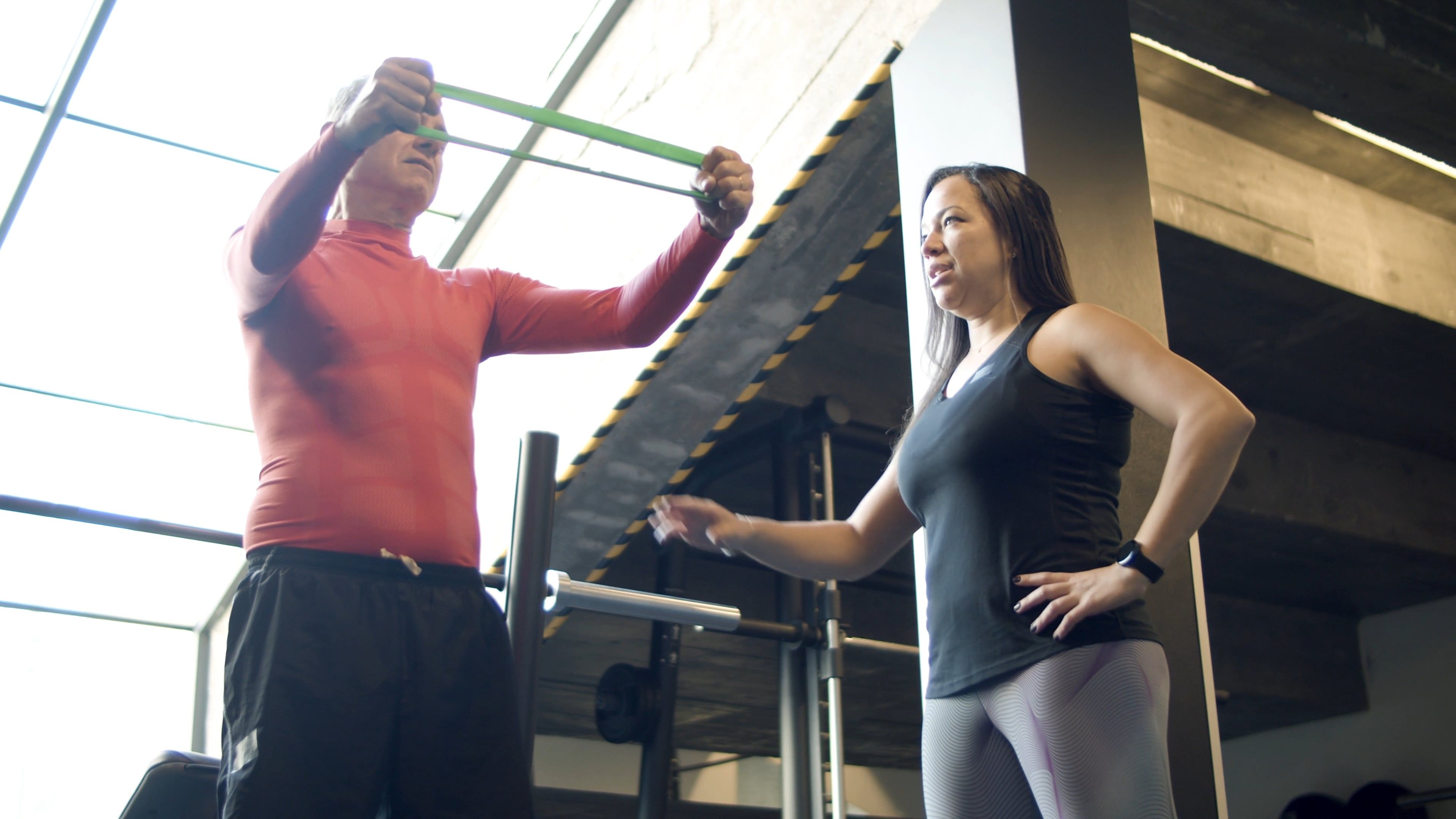 A Man Using an Exercise Band while being Supervised by His Instructor ...