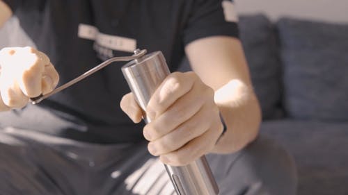 A Person Using a Handheld Coffee Grinder