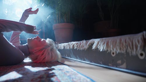 Woman with Bleached Hair Smoking while Lying on the Floor