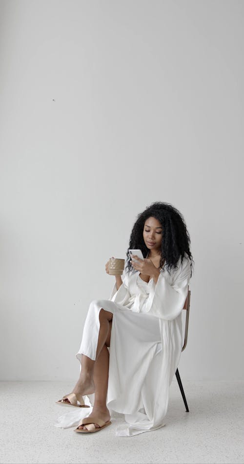 Woman Sitting on a Chair While Using Cellphone