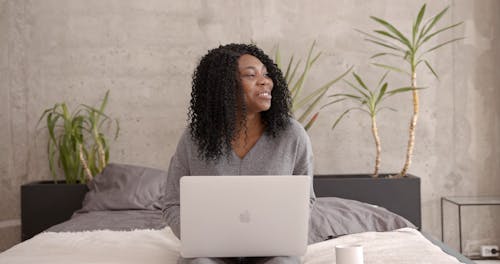 Woman Smiling while Using a Laptop