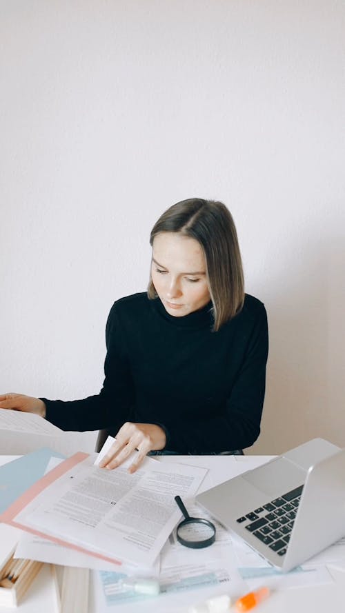 Businesswoman Reading Papers and Typing on Computer