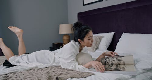 A Woman Reading a Magazine in Bed 