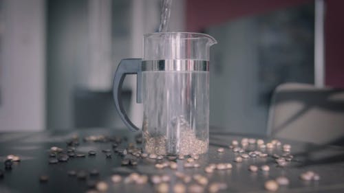 Hot Water Being Poured into Glass Pitcher with Ground Coffee