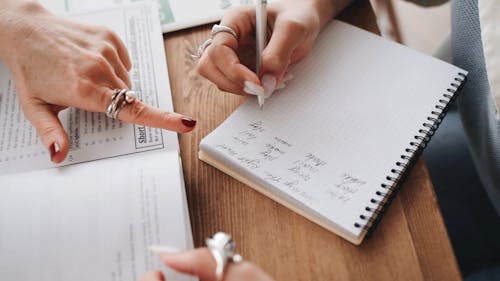 Close-Up View of a Person Writing Notes on Her Notebook