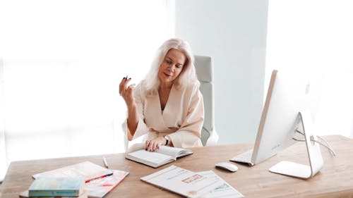 Woman Sitting on a Chair While Writing on a Notebook