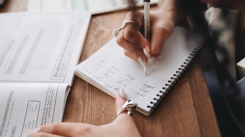 Close-Up View of a Person Writing Notes on Her Notebook