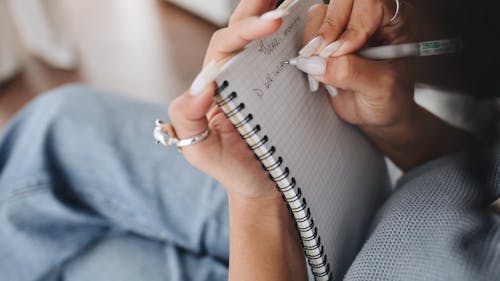 Close-Up View of a Person Writing Notes on Her Notebook