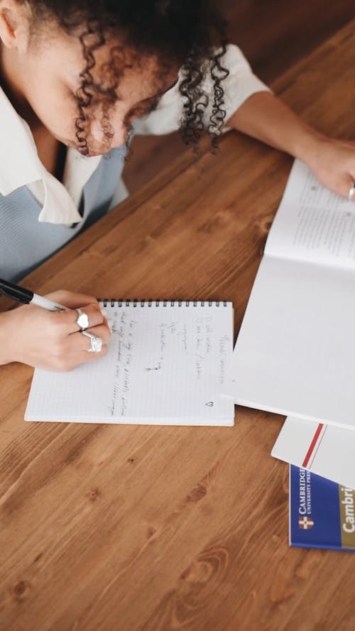 Person Listening While Writing Notes on Her Notebook · Free Stock Video