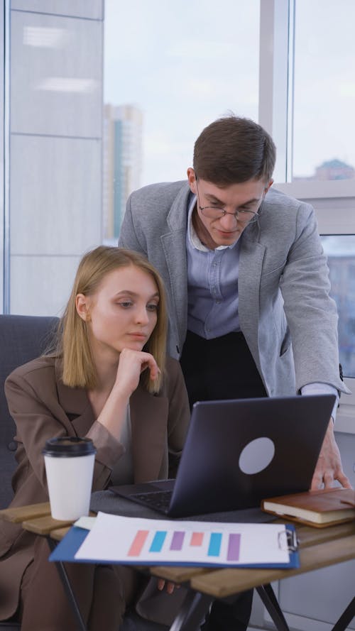 A Man and Woman Discussing while Looking at Laptop