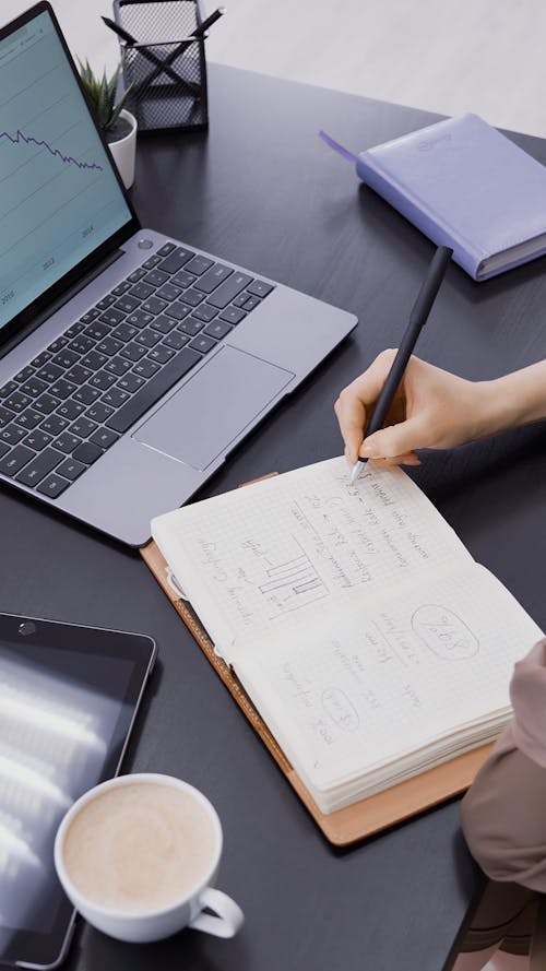 Person Writing on a Notebook