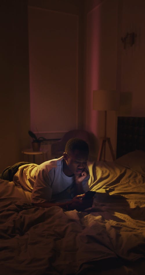 A Man Using a Mobile Phone on Bed
