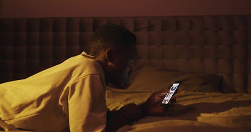 A Man Using His Phone in Bed