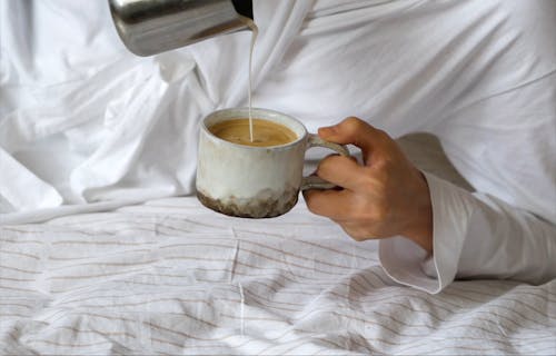 A Person Pouring Milk on a Cup of Coffee