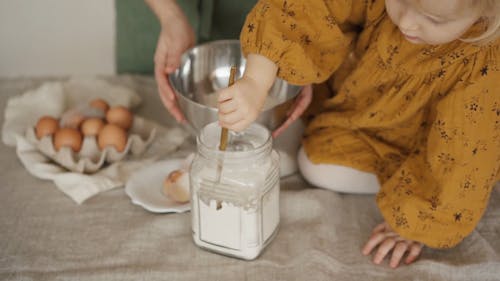 Child Pouring Flour on a Bowl