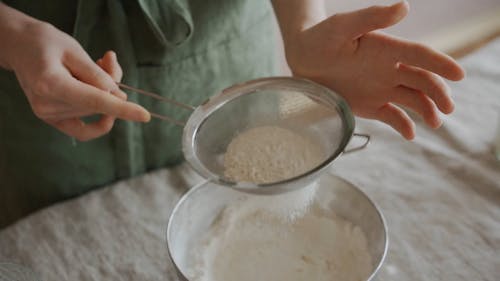 A Person Sifting Flour into a Bowl