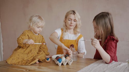 A Mother and Her Daughters Painting Easter Eggs