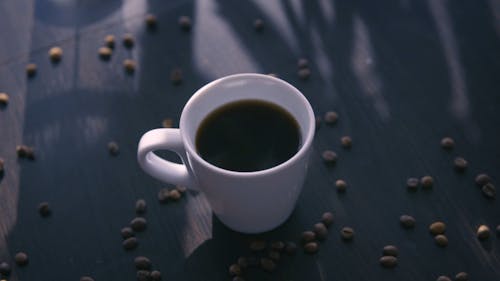 A Cup of Black Coffee and Scattered Coffee Beans