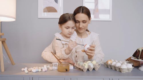 A Mother and Her Daughter Painting Easter Eggs