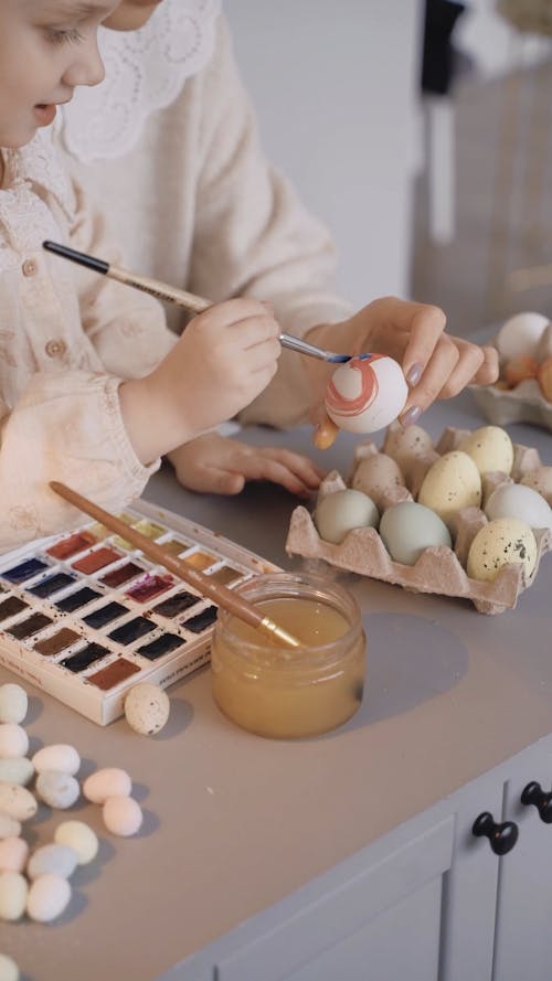 A Mother Teaching Her Daughter how to Paint Eggs