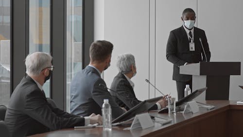 A Man Speaking and Standing at a Podium of a Conference Hall while Wearing a Face Mask