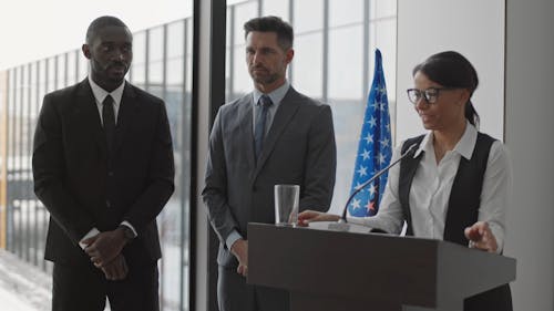 A Woman Having a Speech with Guards Standing on Her Side