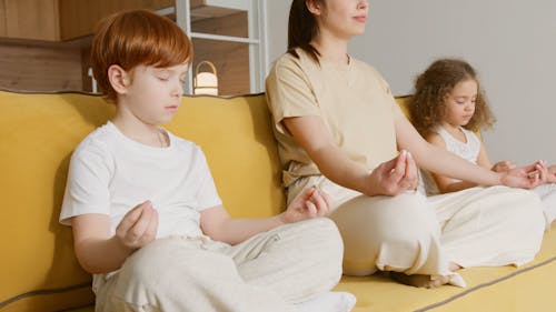 Family Doing  Meditation Yoga While Siting on a Sofa