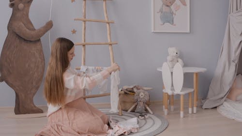 A Woman Hanging The Baby Clothes on the Wooden Ladder