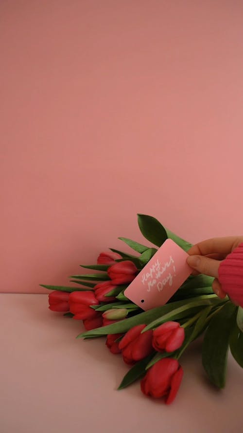 A Woman Putting a Card on a Bouquet of Tulips