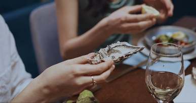 a person squeezing lemon on a fresh oyster
