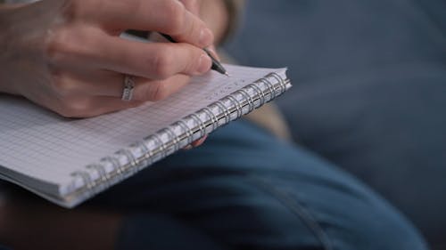 Person Writing on a Notepad