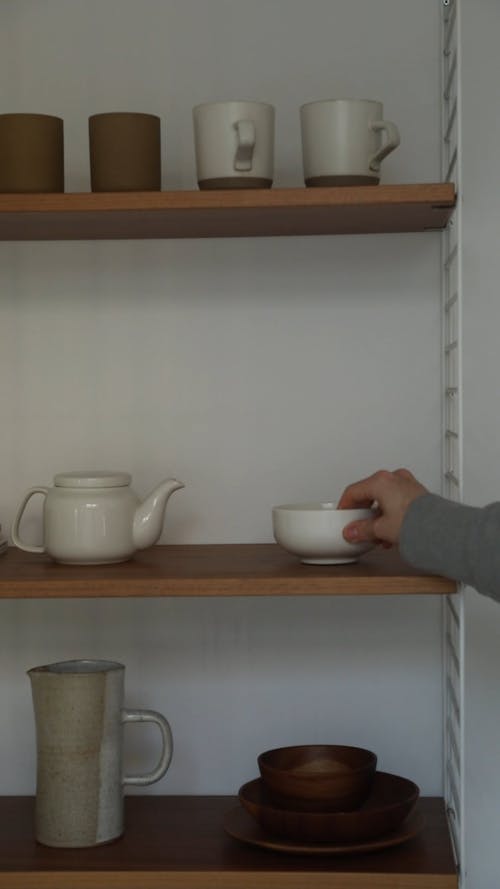 A Person Stacking Bowls on a Shelf