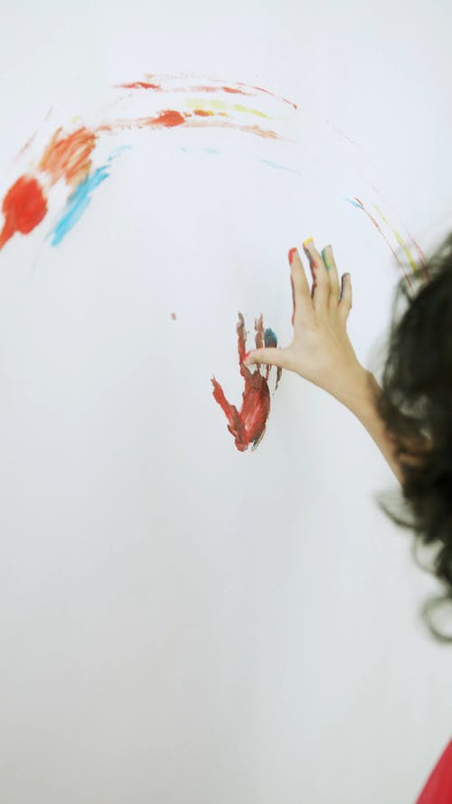 Kid Doing Hand Paint In A White Wall