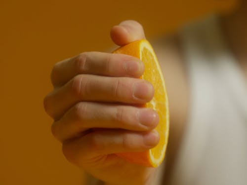 A Young Man Squeezing An Orange To Drink