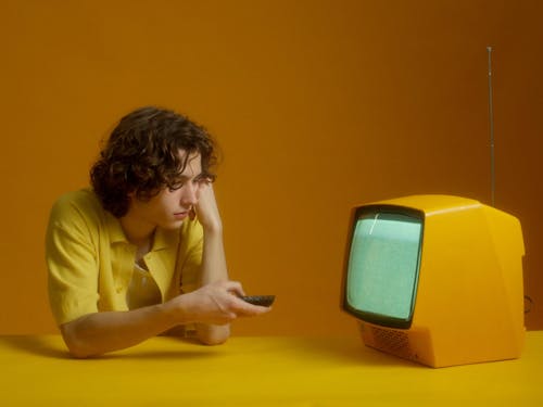 A Young Man Using The TV Remote Control