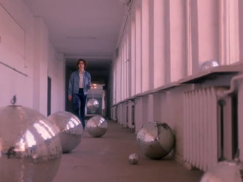 A Man Walking in a Hallway while Carrying a Disco Ball