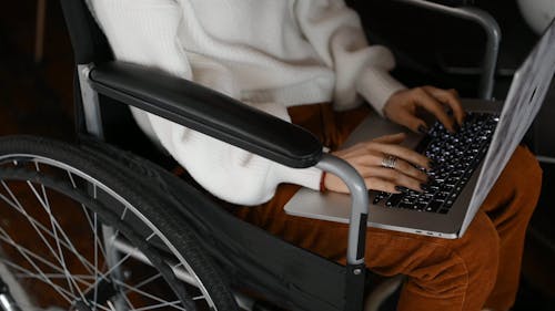 A Person In Wheelchair Using A Laptop