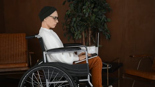 Person Sitting on a Wheelchair While Using a Laptop