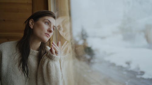 Woman in White Sweater Leaning by the Glass Wall