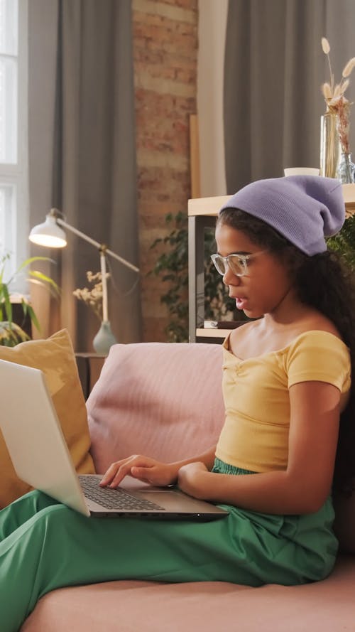 A Little Girl Talking while Looking at a Laptop