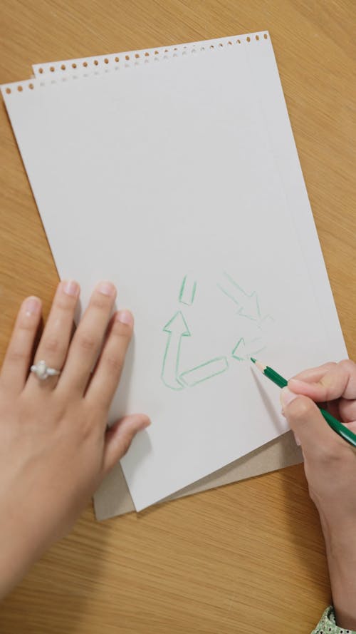 Person Drawing the Recycling Symbol on a Paper