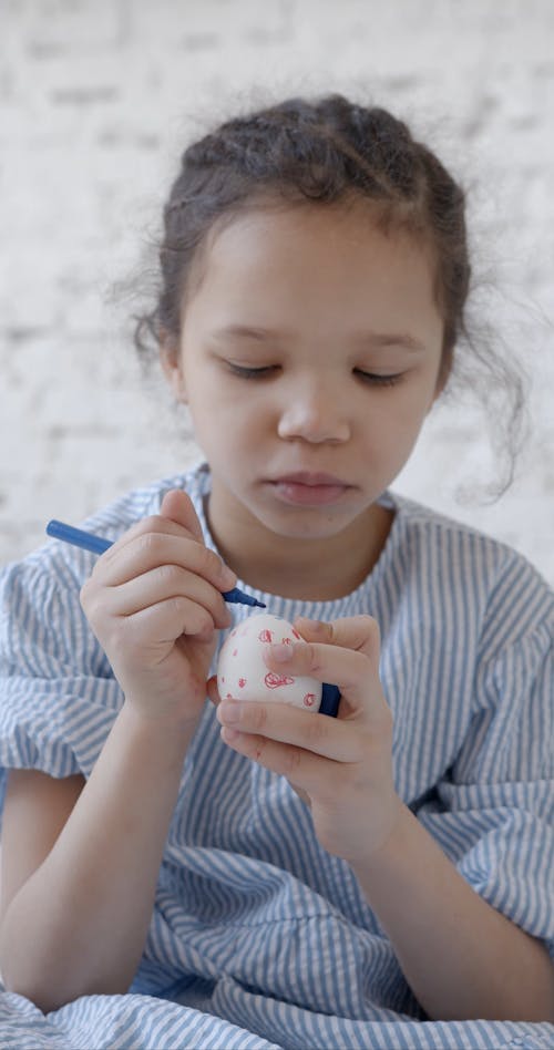 Girl Coloring and Designing an Easter Egg