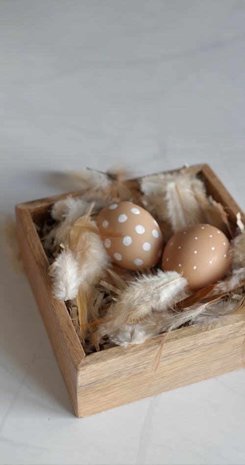 Person Putting a Brown Easter Egg on a Wooden Tray