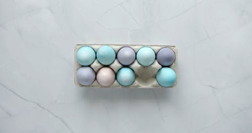 Person Putting a Pastel Painted Egg on a Tray