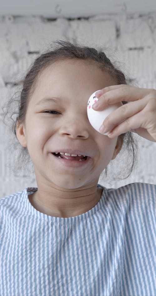 A Girl Covering Her Eye with a Decorated Egg