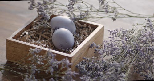 Close-Up View of Person Putting a Purple Easter Egg on a Wooden Tray