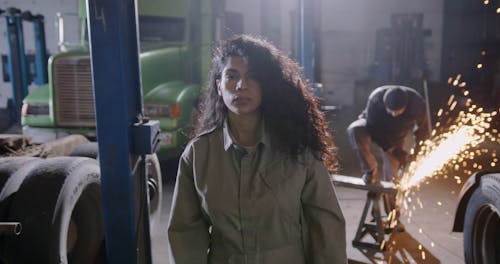 A Woman Looking in the Camera while in the Car Workshop
