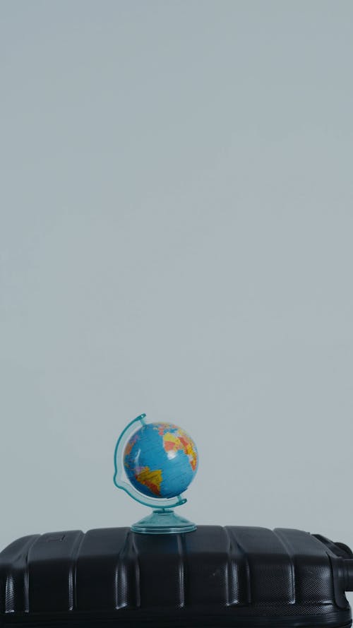 Person Holding Passport Above Small Globe