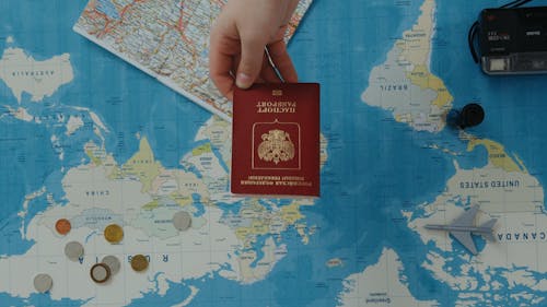 Person Holding a Passport on Top of a World Map