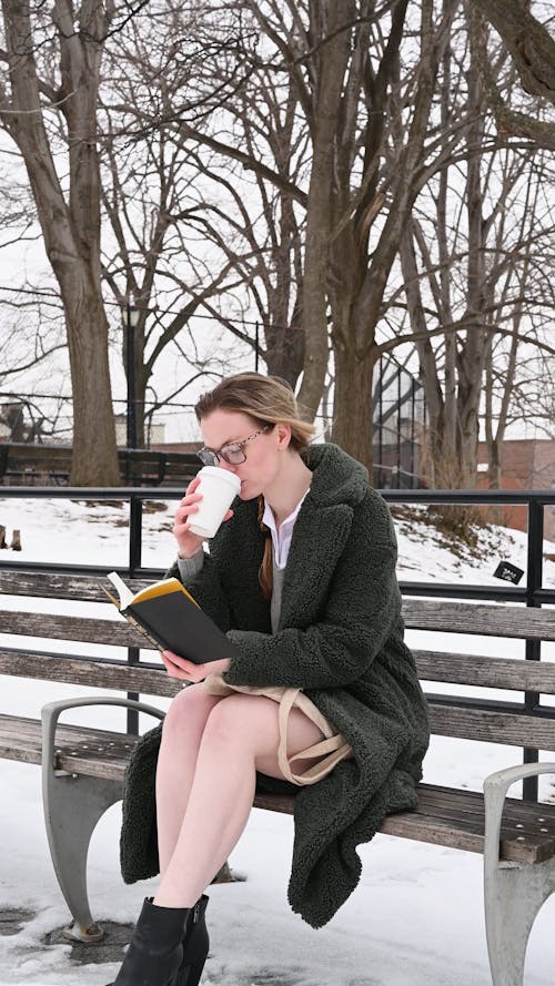 Woman Reading a Book while Sitting on the Bench